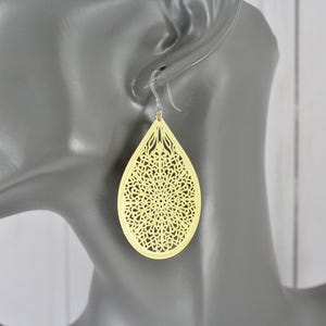 May include: A pair of gold-tone earrings with a delicate, intricate, laser-cut design in the shape of a teardrop.