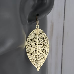 May include: Gold leaf-shaped earrings with a delicate, intricate design. The earrings are lightweight and dangle from a simple hook.