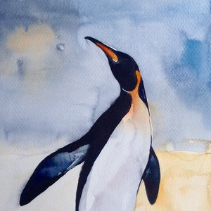Puede incluir: Pintura acuarela de un ping&uuml;ino rey de pie en una playa de arena con un cielo azul de fondo. El ping&uuml;ino est&aacute; mirando hacia la derecha y hacia arriba. La firma del artista est&aacute; en la esquina inferior derecha.