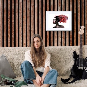 May include: A woman sits on a couch with a guitar and a framed watercolor painting of a woman with red hair. The painting is on a wood panel wall.
