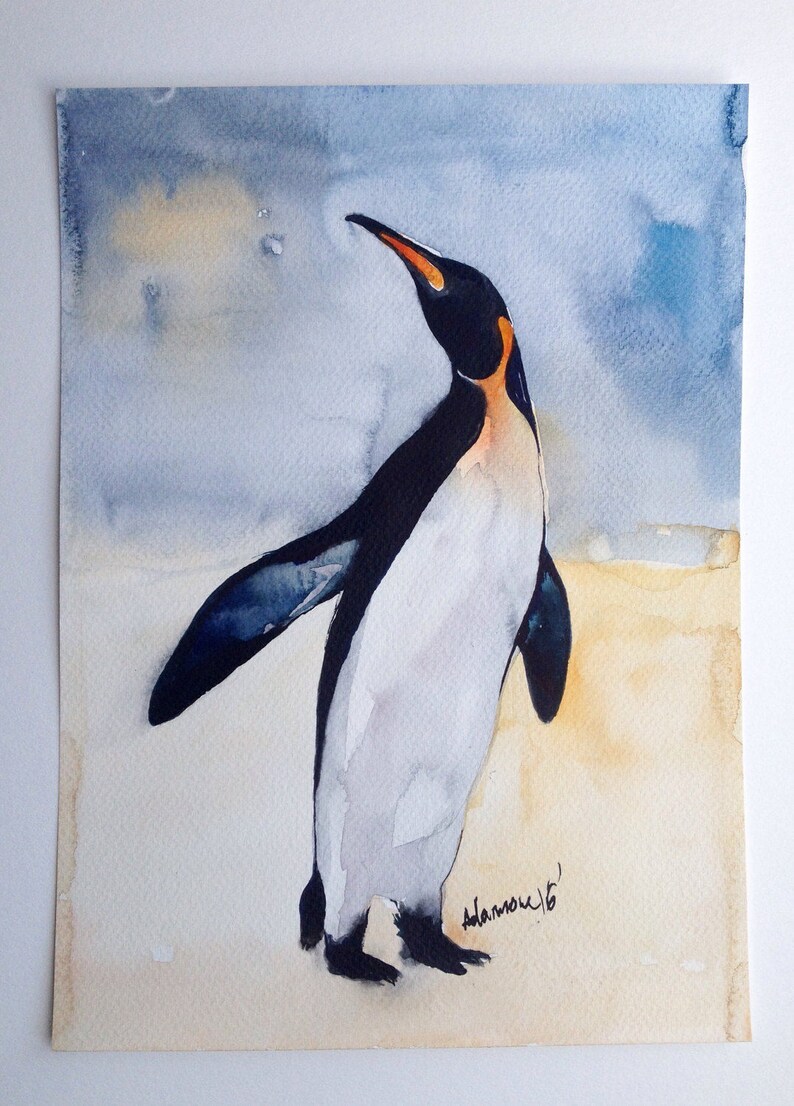 Puede incluir: Pintura acuarela de un ping&uuml;ino de pie sobre un fondo marr&oacute;n claro con un cielo azul en el fondo. El ping&uuml;ino est&aacute; mirando hacia la derecha y tiene un cuerpo blanco y negro con un pico naranja. La firma del artista est&aacute; en la esquina inferior derecha.