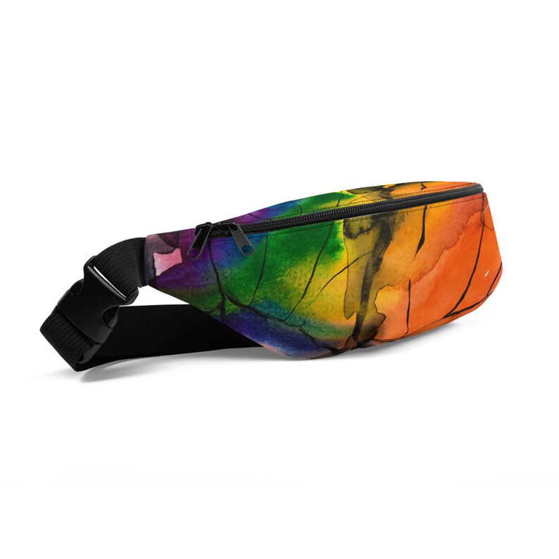 May include: A rainbow-coloured fanny pack with a black adjustable strap and zipper closure. The pack features a watercolour-style design with shades of red, orange, yellow, green, blue, and purple.