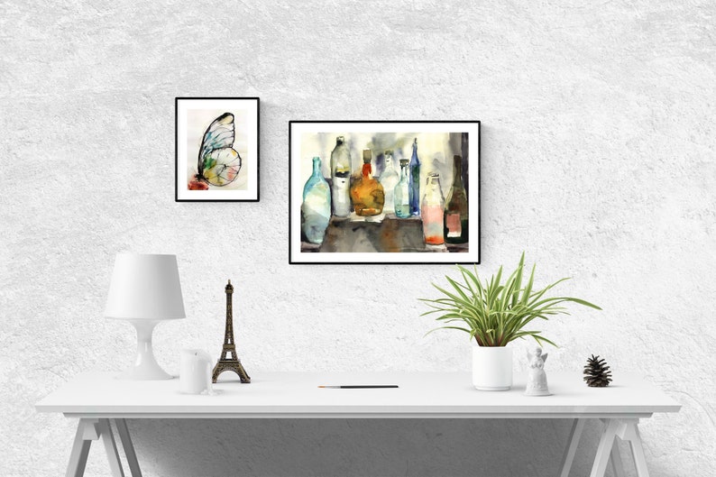 Puede incluir: Una pintura de acuarela de un bodeg&oacute;n con una colecci&oacute;n de botellas de vidrio de varias formas y tama&ntilde;os. Las botellas est&aacute;n dispuestas sobre una mesa y est&aacute;n llenas de l&iacute;quidos de diferentes colores. La pintura est&aacute; enmarcada en negro y est&aacute; colgada en una pared blanca.