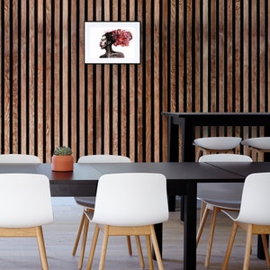 May include: A black and white framed print of a woman with red hair. The woman is looking to the side and has a serious expression. The print is hanging on a wood wall.