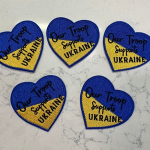 May include: Five blue and yellow heart-shaped patches with the text "Our Troop Supports Ukraine" embroidered on them.