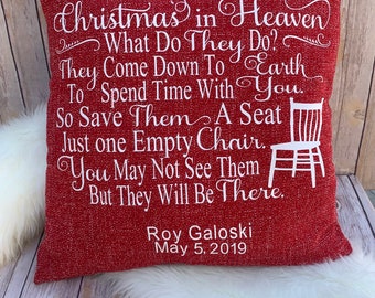May include: Red throw pillow with white text that reads "Christmas in Heaven What Do They Do? They Come Down To Earth To Spend Time With You. So Save Them A Seat Just One Empty Chair. You May Not See Them But They Will Be There."  The pillow also has a white image of a chair and the text "Roy Galoski May 5, 2019".