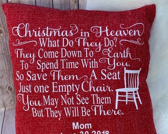 May include: Red throw pillow with white text that reads "Christmas in Heaven What Do They Do? They Come Down To Earth To Spend Time With You. So Save Them A Seat Just One Empty Chair. You May Not See Them But They Will Be There. Mom June 30, 2018".