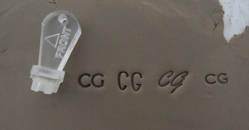 May include: A clear plastic stamp with the word "FRONT" printed on it. The stamp is used to create impressions of the letters "CG" in clay. The letters are shown in four different styles.