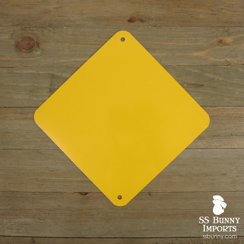May include: A yellow diamond shaped sign with rounded corners and four holes in the corners. The sign is made of metal and has a smooth surface.