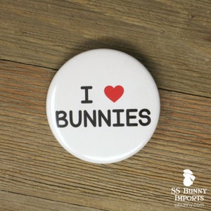 May include: White button with the text "I love bunnies" in black lettering and a red heart.
