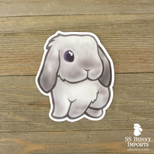 Puede incluir: Un conejo de dibujos animados gris y blanco con orejas ca&iacute;das y un solo ojo azul. El conejo est&aacute; sentado sobre sus patas traseras con sus patas delanteras metidas.
