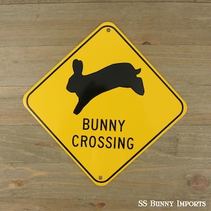 K&ouml;nnte beinhalten: Ein gelbes, rautenf&ouml;rmiges Schild mit einer schwarzen Silhouette eines springenden Kaninchens. Das Schild lautet "Bunny Crossing".