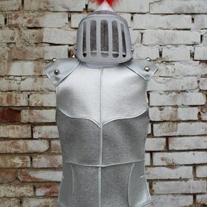 Puede incluir: Traje de armadura plateado con un casco de plumas rojas. El texto "armatura + elmo" est&aacute; en el lado izquierdo de la imagen y "armor + helmet" est&aacute; en el lado derecho de la imagen.