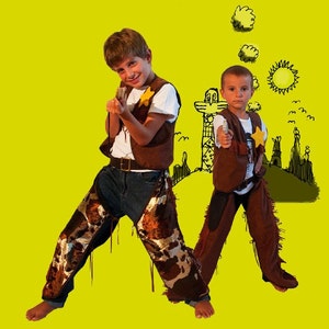May include: Two children wearing white t-shirts, brown vests with yellow star badges, and brown chaps over blue jeans. One child wears cow-print chaps, while the other wears solid brown chaps. Both hold toy pistols against a bright yellow background.