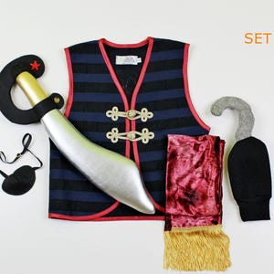 May include: A pirate costume set for kids includes a blue and black striped vest with red trim, a red velvet sash with gold fringe, a black eye patch, a silver plastic sword, a gray hook hand, and a black felt hat.
