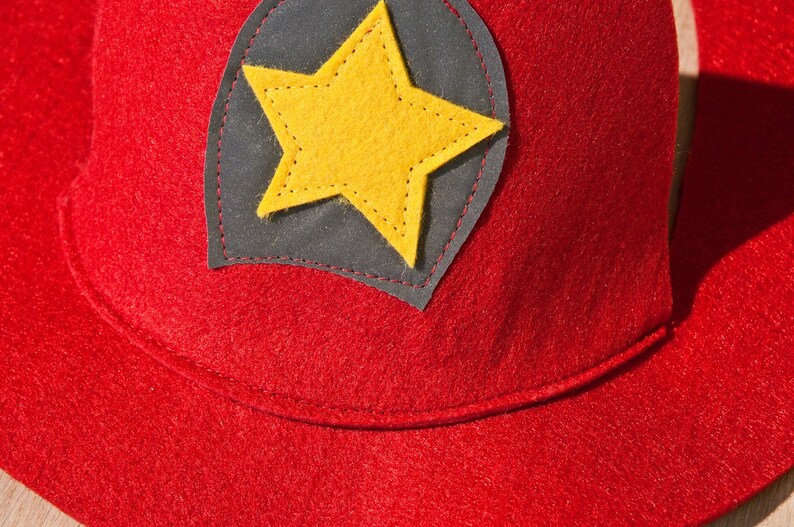 May include: Red felt hat with a black felt star patch. The star is yellow and has stitching around the edges.