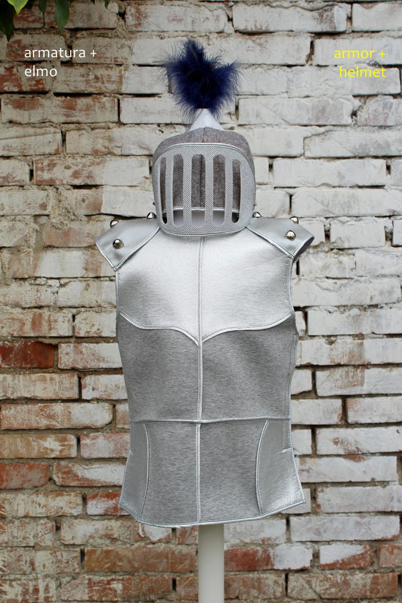 Puede incluir: Un chaleco de armadura de color plateado con un casco gris con una pluma azul en la parte superior. El texto "armatura + elmo" est&aacute; escrito en la esquina superior izquierda y "armor + helmet" en la esquina superior derecha.