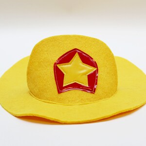 May include: A yellow felt cowboy hat with a red and yellow star patch.