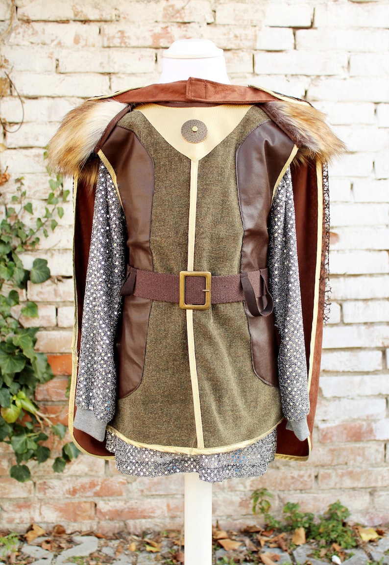 May include: A brown and green costume with a fur collar and a brown belt with a gold buckle. The costume has a gold trim and a chainmail shirt underneath.