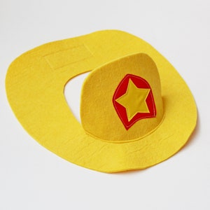 May include: A yellow felt cowboy hat with a red and yellow star patch.