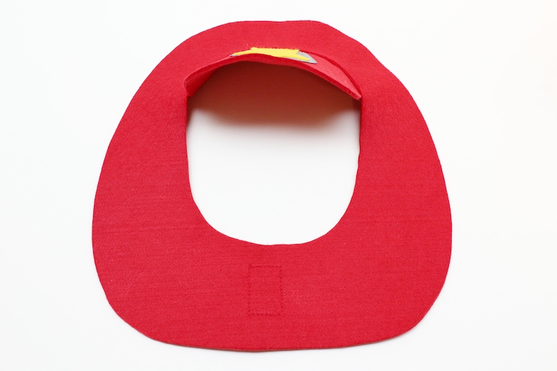 May include: Red felt bib with a yellow and gray felt design on the top. The bib has a velcro closure on the back.