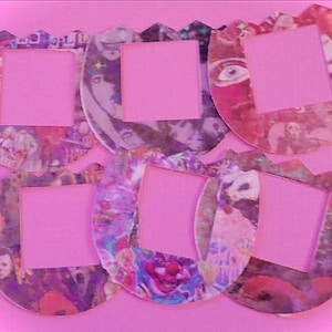 May include: Six colorful, patterned photo frames with a pink background. Each frame has a cutout in the center for a photo.