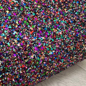 May include: A sheet of colourful glitter with a variety of shapes and sizes. The glitter is a mix of red, orange, yellow, green, blue, purple, and black.
