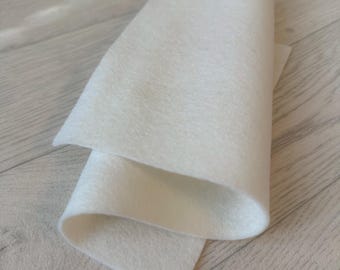 May include: A sheet of white felt fabric folded in half. The felt is soft and smooth, and it is perfect for crafting projects.