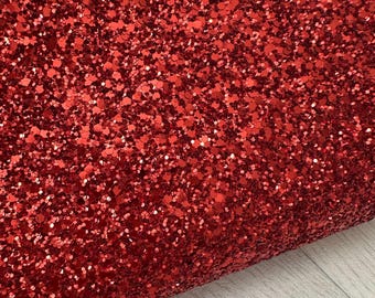 Op de afbeelding: Rode glitterstof met een fijne, glinsterende textuur. De glitter is dicht gepakt, waardoor een glinsterend effect ontstaat.