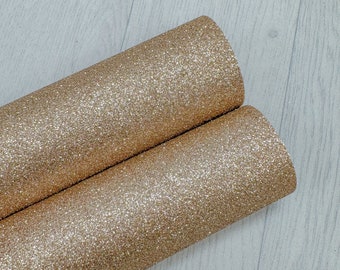 Puede incluir: Dos rollos de tela de purpurina dorada. La tela es de color dorado metálico brillante.