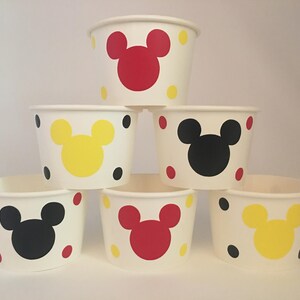 K&ouml;nnte beinhalten: Sechs wei&szlig;e Pappbecher mit roten, gelben und schwarzen Mickey-Maus-Gesichtern und Punkten.