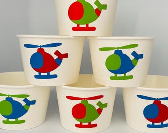 May include: Six white paper cups with a red, blue, and green helicopter design. The helicopters have red, blue, and green bodies with white blades.