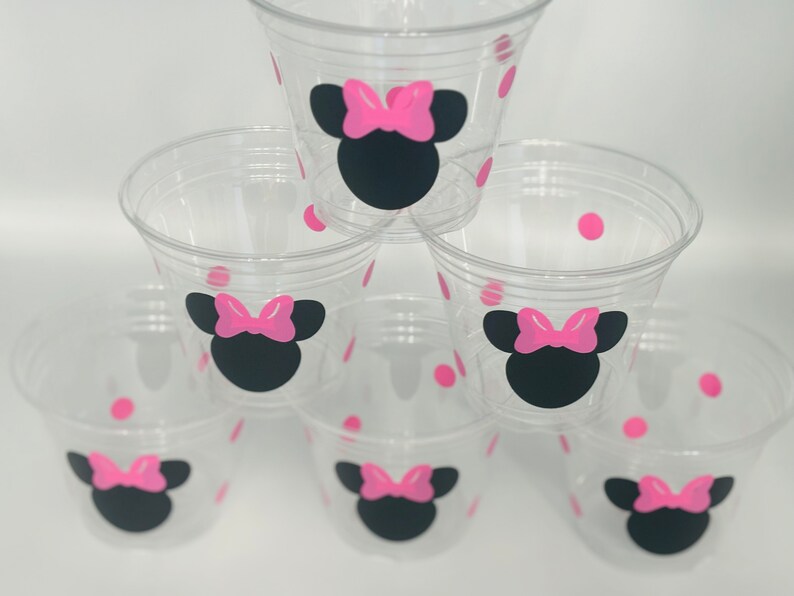 Puede incluir: Seis vasos de pl&aacute;stico transparentes con lunares rosas y un dise&ntilde;o de Minnie Mouse negro y rosa.