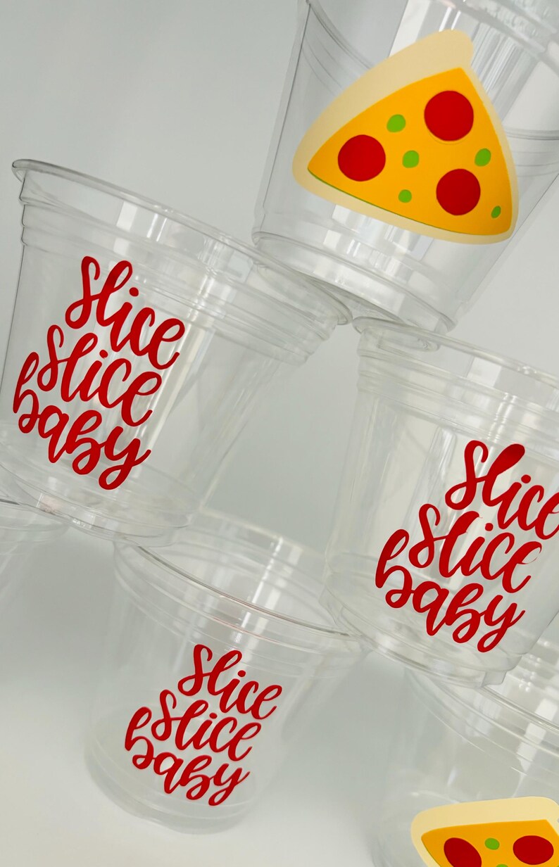 Op de afbeelding: Vier doorzichtige plastic bekers met rode vinyl stickers waarop "Slice Slice Baby" staat. Een beker heeft een gele pizzapunt sticker met rode pepperoni en groene pepers.