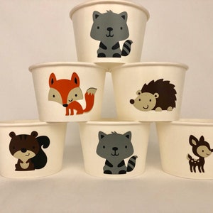 Puede incluir: Seis vasos de papel blancos con diferentes dise&ntilde;os de animales del bosque. Los vasos presentan un zorro, un mapache, una ardilla, un erizo, un ciervo y un gato.