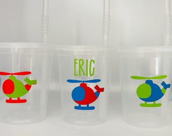 May include: Three clear plastic cups with straws and personalized helicopter designs. The cups have the names "Eric" and a red and blue helicopter, a green and red helicopter, and a green and blue helicopter.