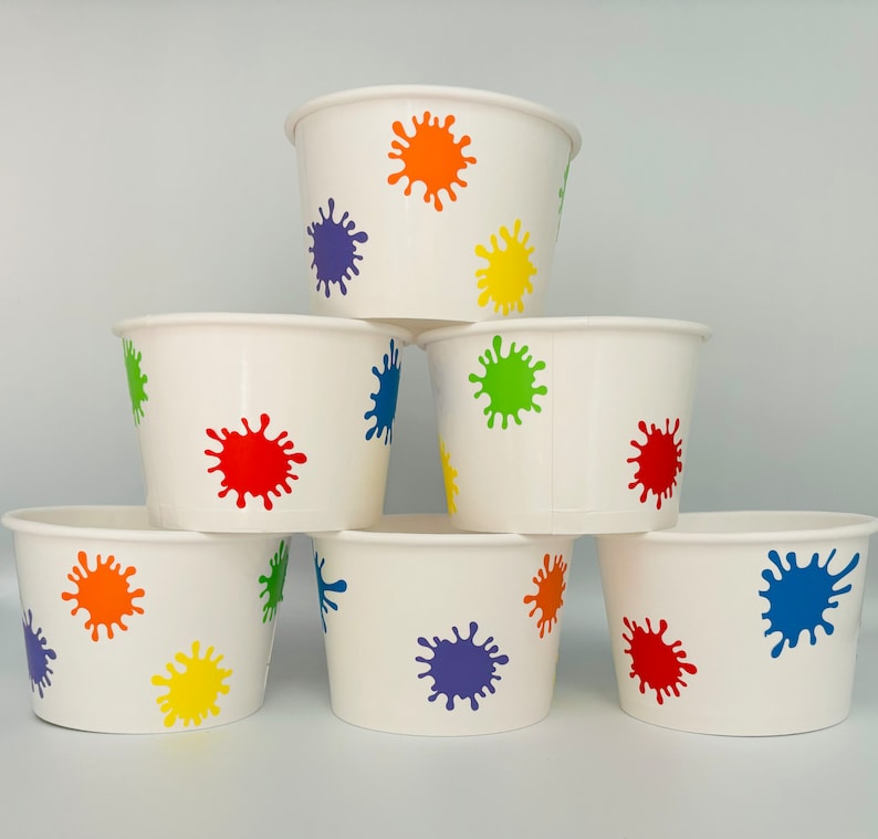 K&ouml;nnte beinhalten: Sechs wei&szlig;e Pappbecher mit bunten Farbklecksmustern. Die Becher sind pyramidenf&ouml;rmig gestapelt. Die Farben der Farbklecksmuster sind rot, orange, gelb, gr&uuml;n, blau und lila.