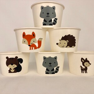 Puede incluir: Seis vasos de papel blancos con diferentes dise&ntilde;os de animales del bosque. Los vasos presentan un zorro, un mapache, un erizo, una ardilla y un ciervo.