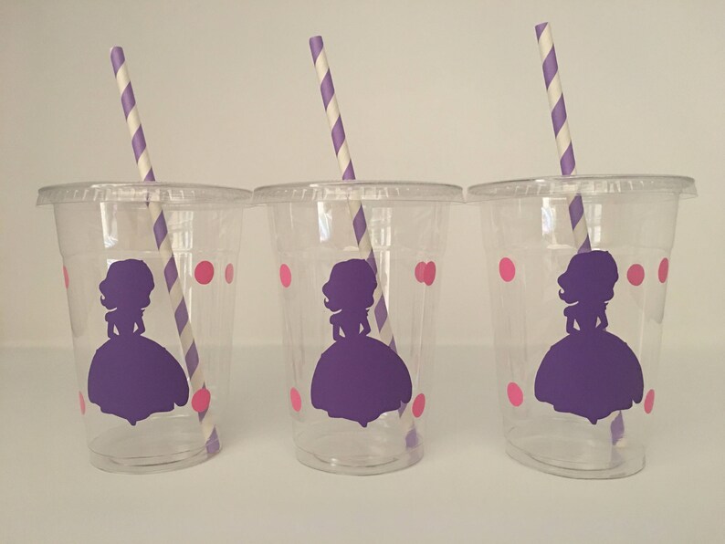 May include: Three clear plastic cups with purple and white striped straws. Each cup has a pink polka dot pattern and a purple silhouette of a princess wearing a dress.