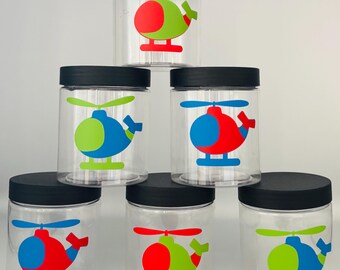 May include: Six clear glass jars with black lids, each decorated with a different colored helicopter design. The helicopters are red, blue, and green with black outlines.