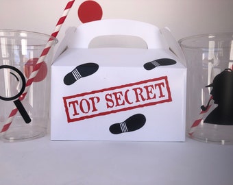 May include: White party favor box with a red "TOP SECRET" stamp and black footprints. Two clear plastic cups with red and white striped straws, one with a magnifying glass and the other with a silhouette of a detective.