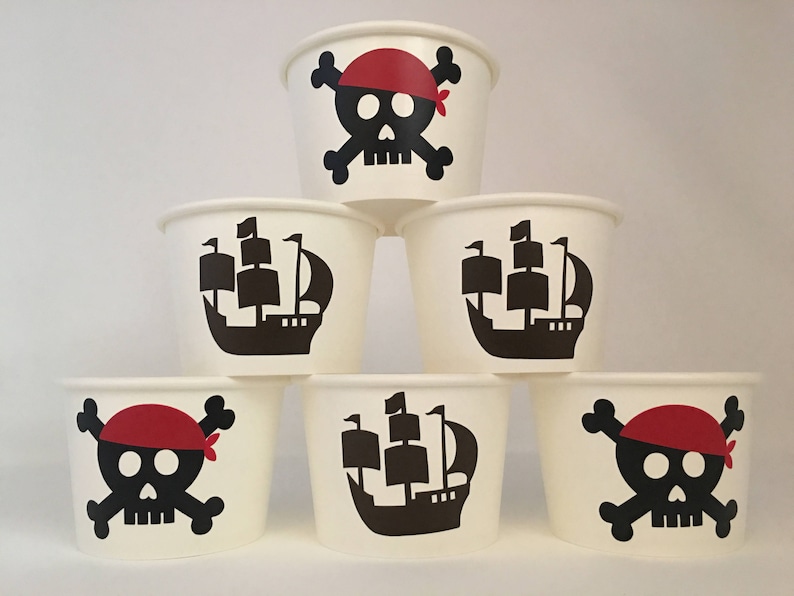 Peut inclure: Six gobelets en papier blanc avec des motifs sur le th&egrave;me des pirates. Trois gobelets pr&eacute;sentent un cr&acirc;ne noir et des os crois&eacute;s avec un bandana rouge. Trois gobelets pr&eacute;sentent un navire noir avec des voiles blanches.