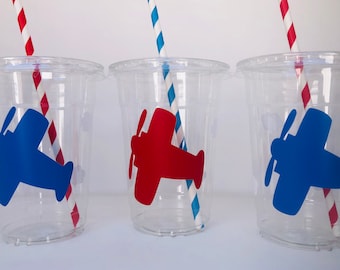 May include: Three clear plastic cups with red and blue airplane stickers and red and white striped straws.