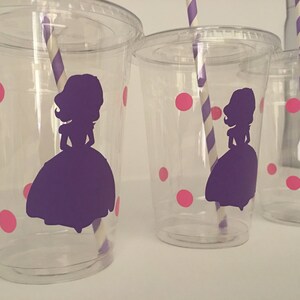 May include: Three clear plastic cups with pink polka dots and a purple silhouette of a princess. Each cup has a striped straw.