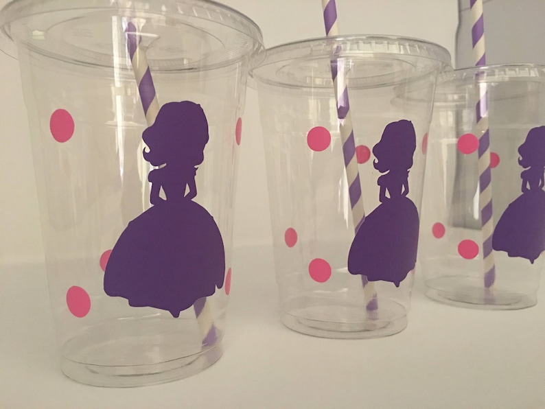May include: Three clear plastic cups with pink polka dots and a purple silhouette of a princess. Each cup has a striped straw.