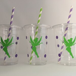 May include: Three clear plastic cups with green fairy silhouettes and purple polka dots. Each cup has a striped paper straw.