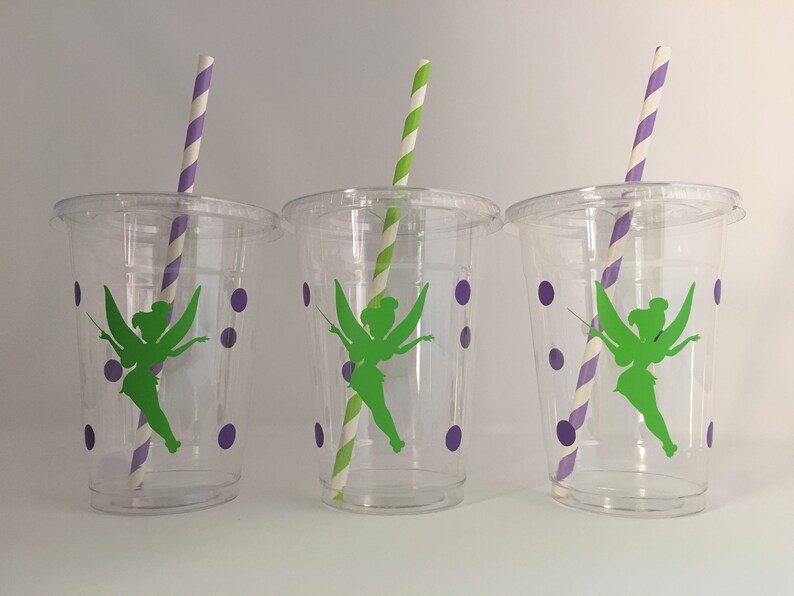 May include: Three clear plastic cups with green fairy silhouettes and purple polka dots. Each cup has a striped paper straw.
