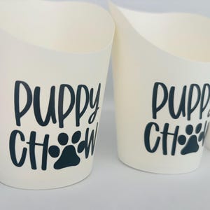 May include: Two white cups with black text that reads "Puppy Chow" with a paw print.