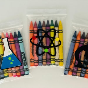 May include: Three clear plastic bags filled with crayons and a science-themed sticker. The stickers are a beaker, an atom, and a microscope. The crayons are Crayola brand.