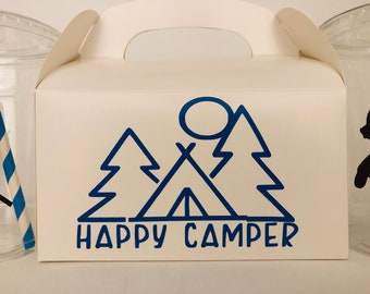 May include: White cardboard box with a blue graphic of a tent, two trees, and a sun. The text "HAPPY CAMPER" is printed below the graphic.